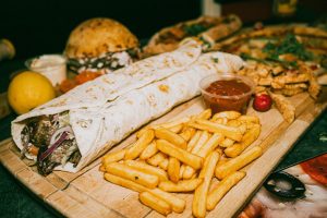 Close-up of a hearty Turkish wrap served with crispy fries and dipping sauce.