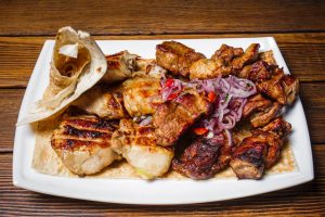 Exquisite grilled meat selection served with onions and flatbread on a wooden table.